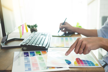 designer Editor at work drawing sketches a new project on graphic tablet and color palette sitting at desk with computer at studio or office