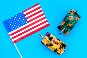 War, military threat, military power concept. USA. Tanks toy near american flag on blue background top view