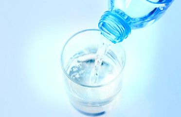 Pour pure water from a bottle of mineral water into a glass.