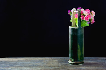 Flowers in bamboo vase on black background.