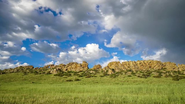 Time lapse of rolling clouds over a rock formation in Loveland, Colorado, Blue sky and green grass. Devils Backbone,