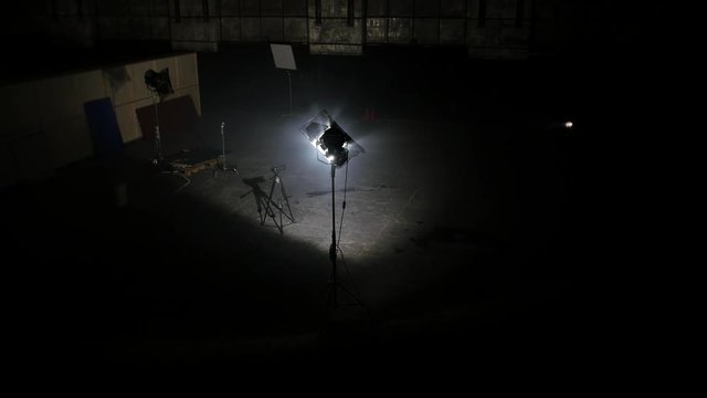 Dark photo studio with light spotlights. Spacious dark room with supplied floodlights and camera on tripod ready for professional shooting