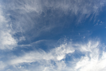 White cirrus clouds in the blue sky on a clear day in the summer. Used as a background image.