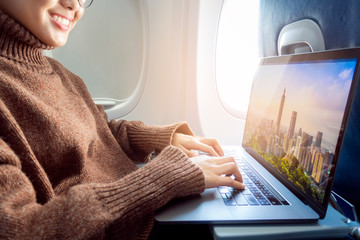 Fototapeta premium Beautiful Asian woman is working with laptop in airplane
