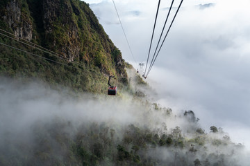 The cable car to mountain top with low clouds and mountain view