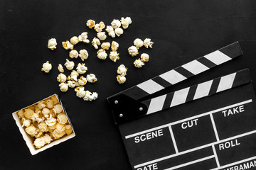Film watching concept. Clapperboard and popcorn on black background top view