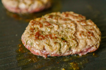 cooking meat burgers with spices on grill at home. Close up, selective focus