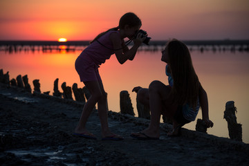 on a salt lake two girls take pictures of each other at sunset