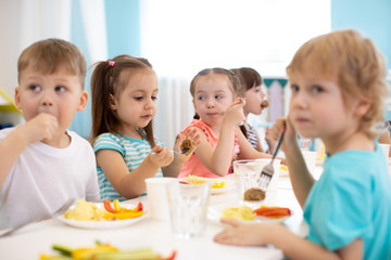 Obraz na płótnie Canvas Group of kindergarten children have lunch in daycare