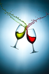 Two Types of Colorful Red and Light Yellow Wine Splashes Poured Out from Glasses Against Bluish...