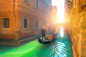 Venice canal, gondola and gondolier with tourists traveling by water in the town. © aapsky