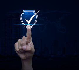 Hand pressing security shield with check mark icon over world map, modern city tower and skyscraper, Internet cyber security and anti virus concept, Elements of this image furnished by NASA