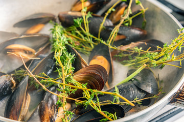 Mussels are cooked in a pan with spices.