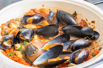 Homemade tasty sauce with mussels and vegetables in a pan.