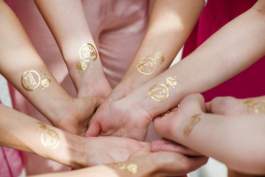 Macro shot of temporary tattoo of a ring on bridesmaids hands held together. Cheerful bride and bridesmaids party before wedding. Women having fun 
