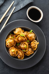 Asian dumplings in bowl, chopsticks, plates. Asian table setting. Chinese dumplings for dinner. Selective focus. Asian style decoration. Chinese fresh homemade food. Closeup
