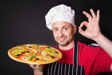 Portrait of happy attractive cook with a pizza in hands