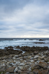 Ocean waves crashing on rocks, coastline view in California. Sand and rocks on a beach