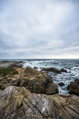 Fototapeta na wymiar Ocean waves crashing on rocks, coastline view in California. Sand and rocks on a beach