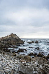 Fototapeta na wymiar Ocean waves crashing on rocks, coastline view in California. Sand and rocks on a beach