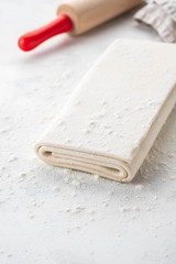 Homemade raw puff pastry on a white background.