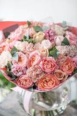 beautiful fresh cut bouquet of mixed flowers in vase on wooden table. . the work of the florist at a flower shop. Delicate Pastel tones color