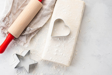 Raw puff pastry dough lies on a white table. Figures for baking cut metal mold. Copy space, top view.