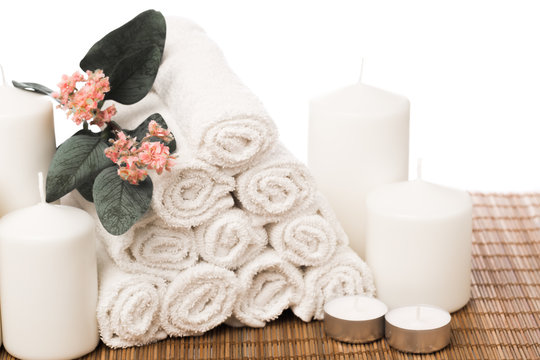 set of white roll towels with flowers and candles isolated on white.