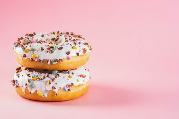 Donuts with icing on pastel pink background. Sweet donuts. Copy space.