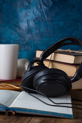 Books are stacked, Headphones, White Cup, open Diary on a wooden background. The Concept of Audio Books
