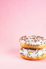 Donuts with icing on pastel pink background. Sweet donuts. Copy space.