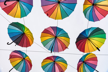 Fototapeta na wymiar Rows of rainbow colored umbrellas hanging in the air