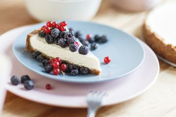 Slice of cheesecake with red currant and blackberries