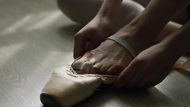 Close-up of ballerina's feet. Close-up of calloused, bandaged with patches, feet ballerina sitting on floor and preparing for another grueling workout