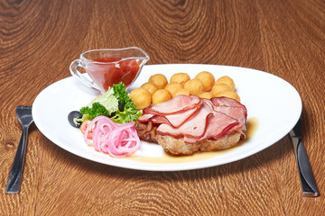 roast pork on which lies meat sliced into thin slices, cheese balls, onion rings, olives, lettuce and a little cilantro with cherry tomatoes