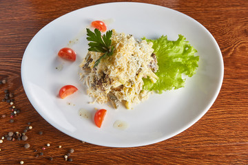 salad of beef tongue, cheese, eggs, pickled cucumbers and French fries, on a lettuce, with cherry tomatoes, next to a plate a mixture of peppers