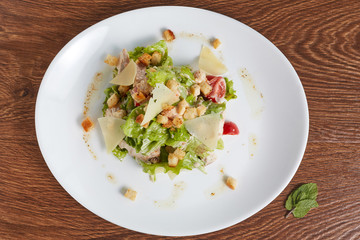 salad of cherry tomatoes, cheese, crackers, pork and lettuce petals, next to a white plate is mint