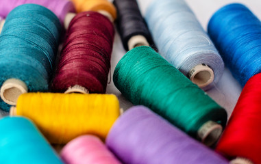 background shot of many bright thread spools on white fabric - image