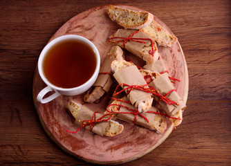 Delicious biscotti cookies with dried cherries and hazelnuts with black tea and white cup. Organic style. White cup of tea.