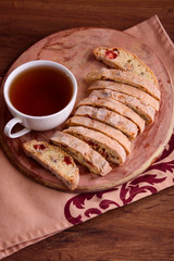 Delicious biscotti cookies with dried cherries and hazelnuts with black tea and white cup. Organic style. White cup of tea.