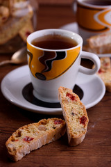 Delicious biscotti cookies with dried cherries and hazelnuts with black tea and white cup. Organic style. White cup of tea.
