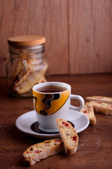 Delicious biscotti cookies with dried cherries and hazelnuts with black tea and white cup. Organic style. White cup of tea.
