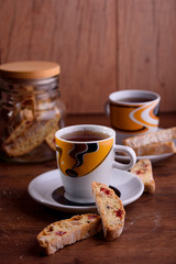 Delicious biscotti cookies with dried cherries and hazelnuts with black tea and white cup. Organic style. White cup of tea.