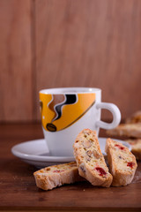Delicious biscotti cookies with dried cherries and hazelnuts with black tea and white cup. Organic style. White cup of tea.