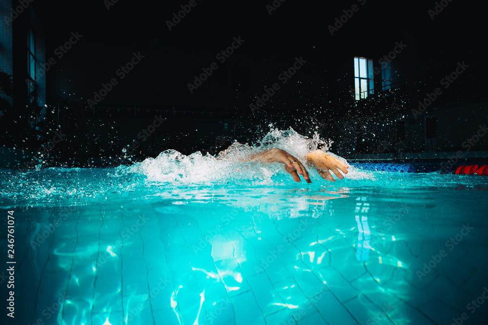 Wall mural Professional woman swimmer swim using breaststroke technique on the dark background