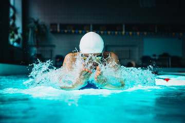Professional woman swimmer swim using breaststroke technique on the dark background - obrazy, fototapety, plakaty