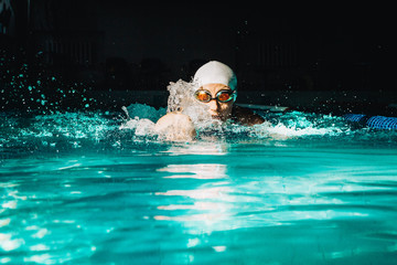 Professional woman swimmer swim using breaststroke technique on the dark background