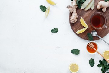 Hot tea with ginger, lemon, honey and mint leaves on white table.Tea against cold.Healthcare concept.Useful tea for immunity.Eyer bird view