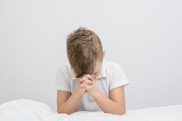 Young boy  praying in bedroom before going to bed