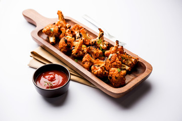 Tandoori Gobi / Roasted cauliflower Tikka is a dry dish made by roasting Cauliflowers in Oven/Tandoor. It's  popular starter food from India. served with ketchup. selective focus